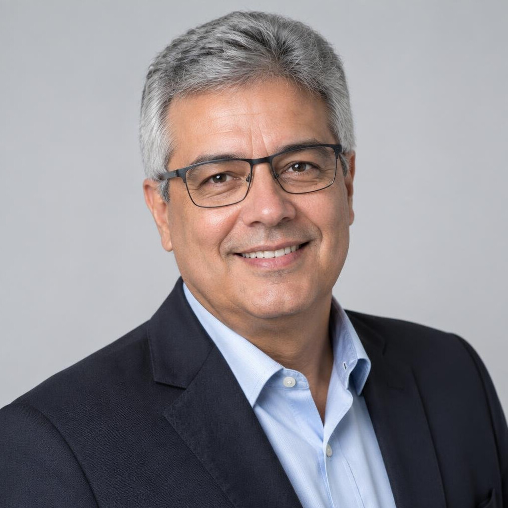 Studio portrait of a Brazilian man in his 50s with glasses smiling