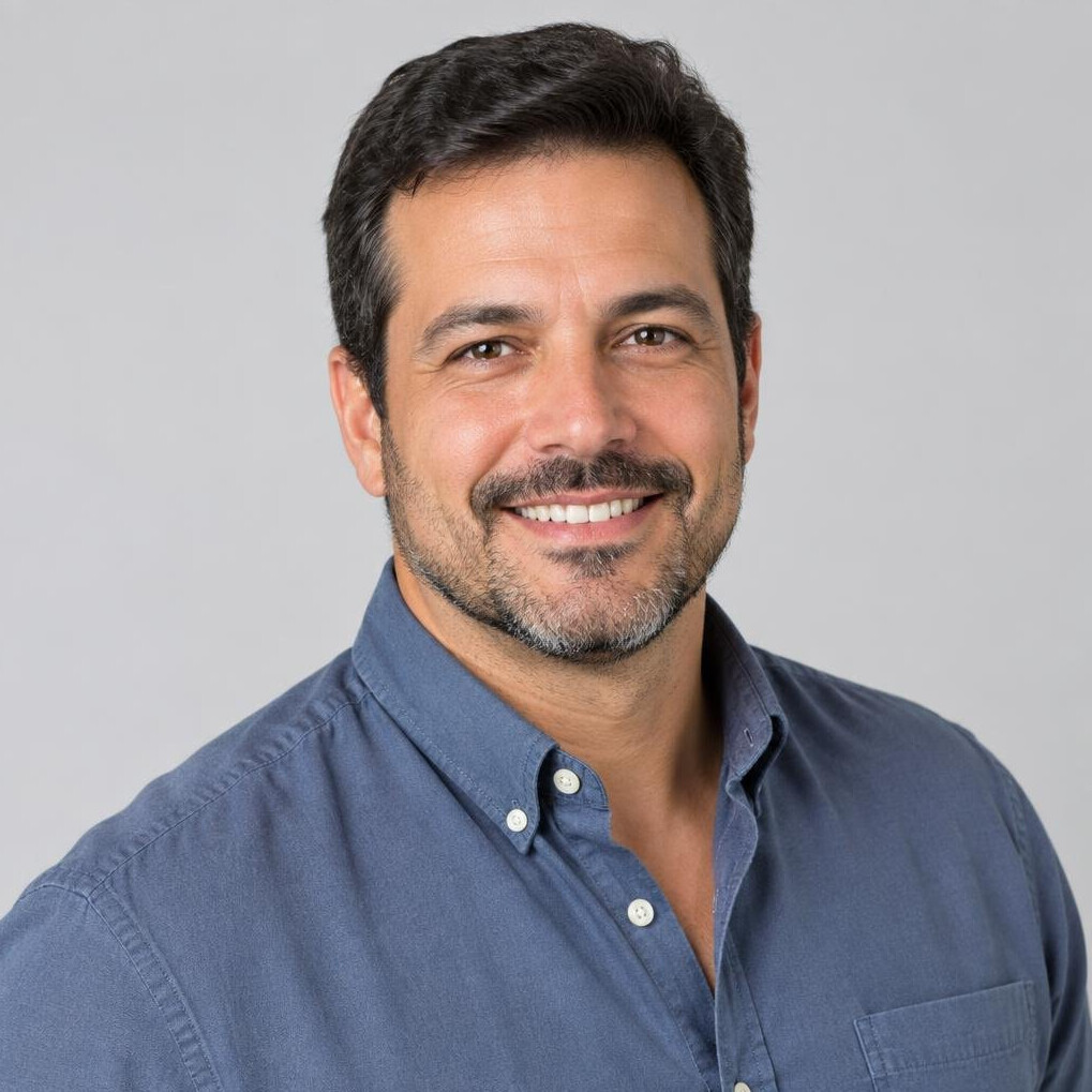 Studio portrait of a Brazilian man in his 40s smiling in a casual shirt